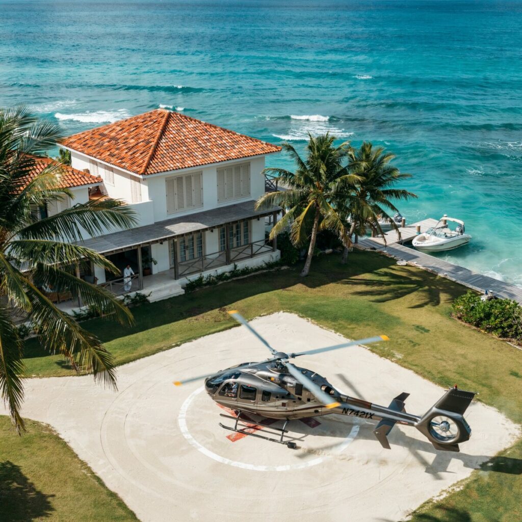 Aerial view of private island with turquoise lagoon and luxury villa helipad.